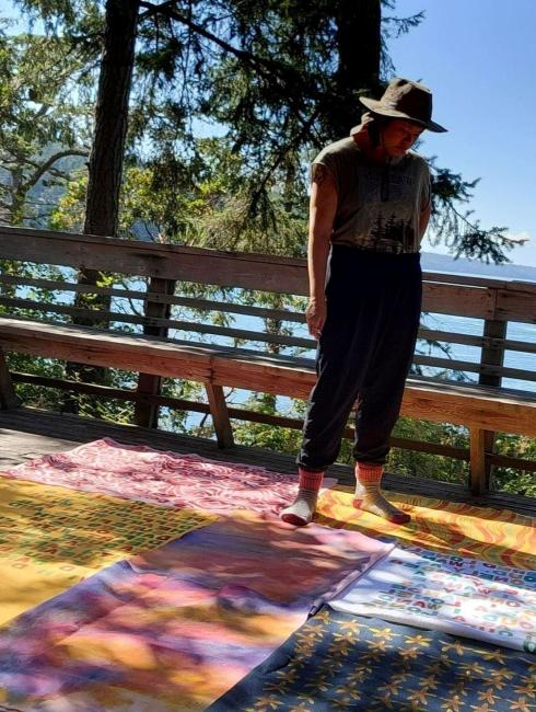 Deception Pass Artist Nina Vichayapai stand on her deck and looks at her art laid out on the floor