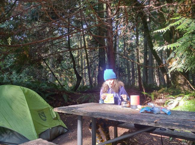 Camper eats a meal at a picnic table