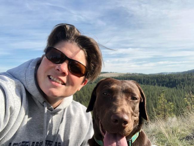 Parks Director Diana Dupuis smiles on a sand dune with her brown dog