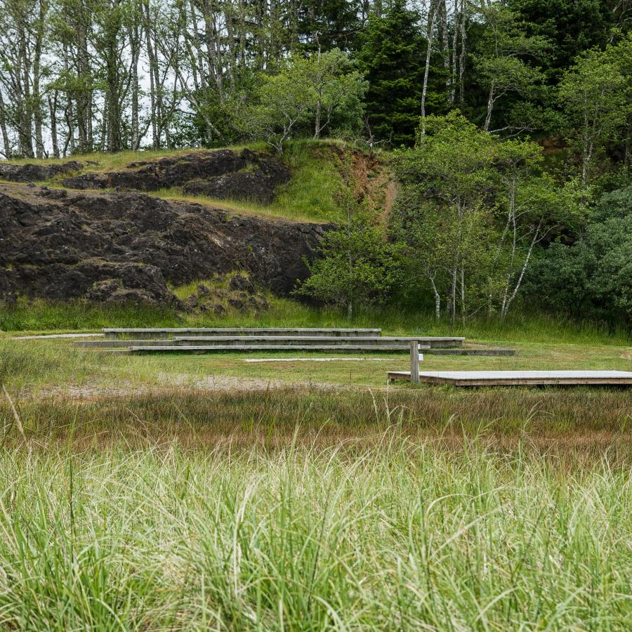 The amphitheater at Cape Disappointment is made of a few benches facing the platform in a grassy field