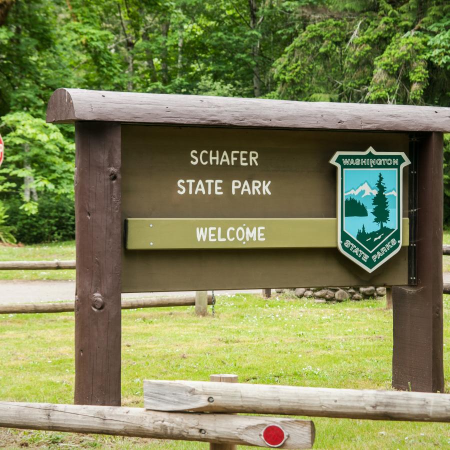 Schafer Welcome sign with trees visible in the background and a fence surrounding the sign.