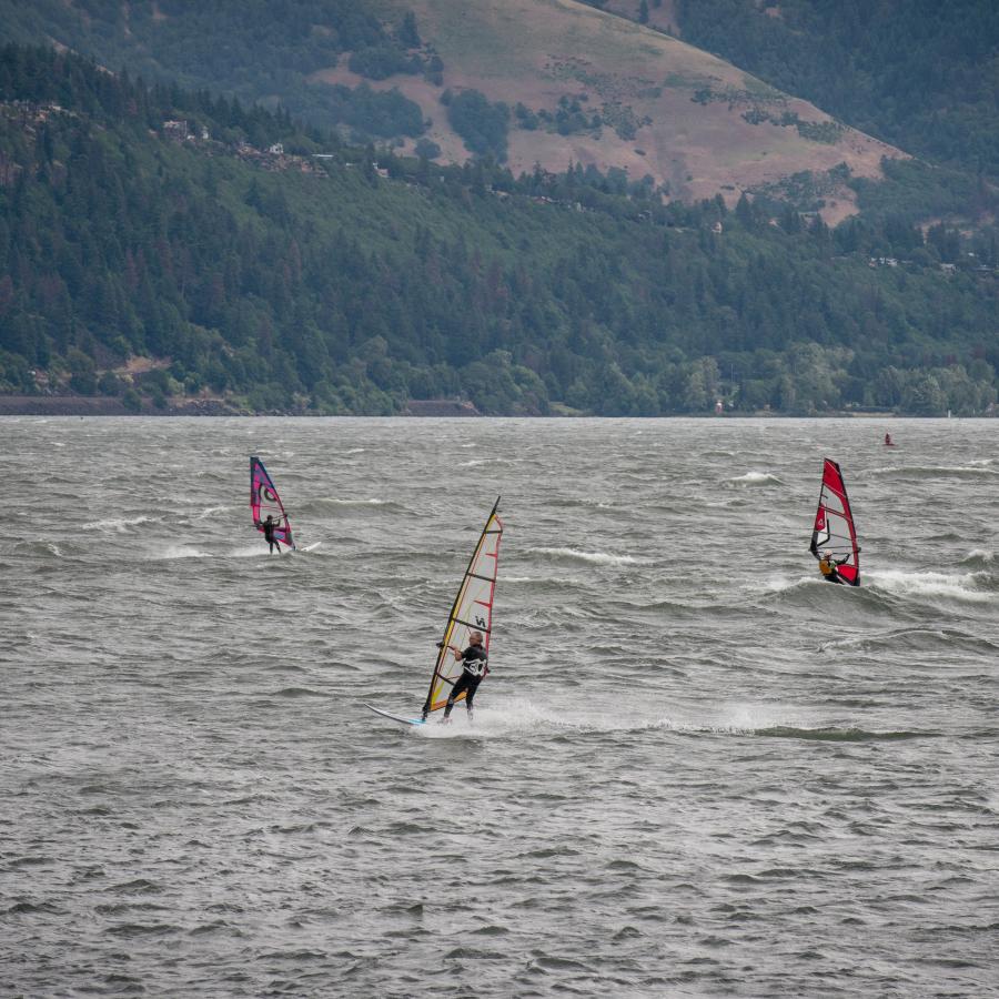 Three wind surfers on windy River.