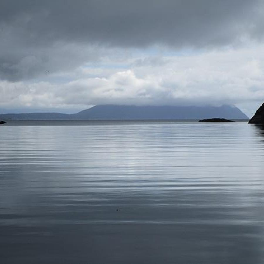 calm water leading out to island shrouded in clouds