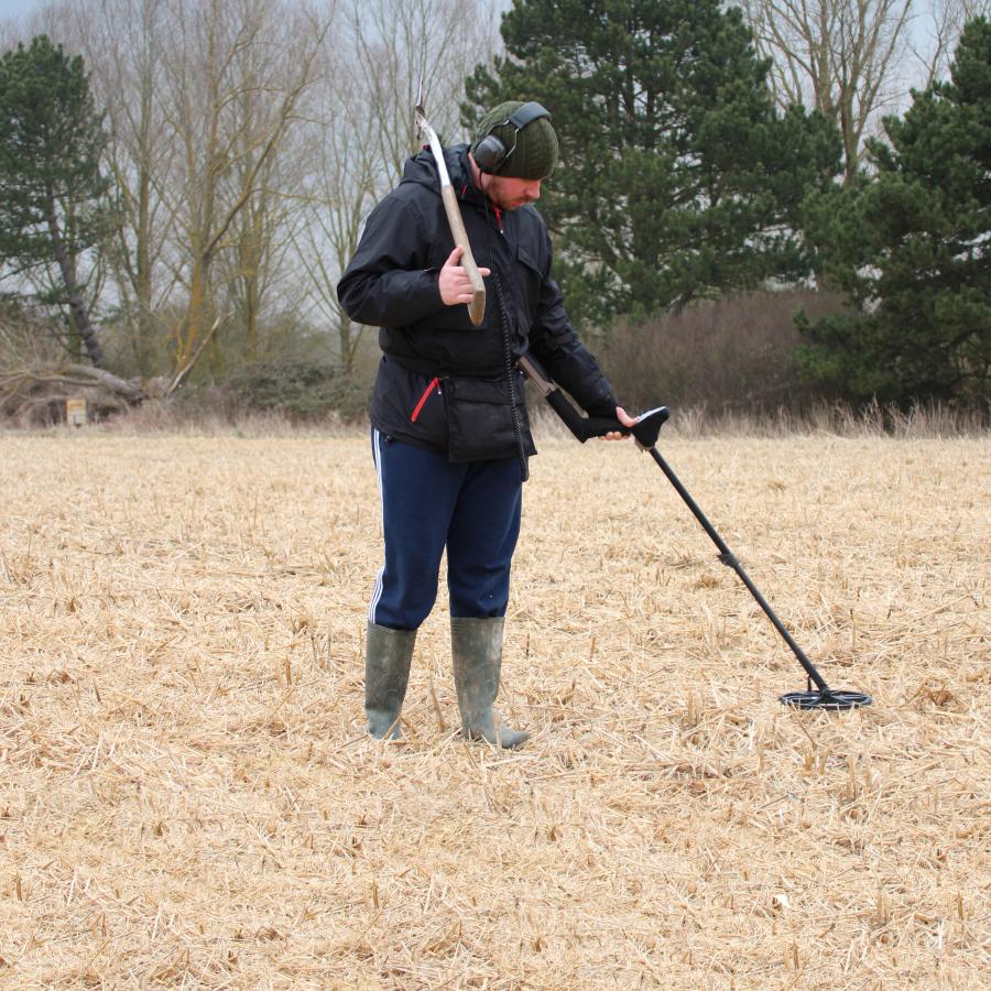 Person metal detecting outdoors.