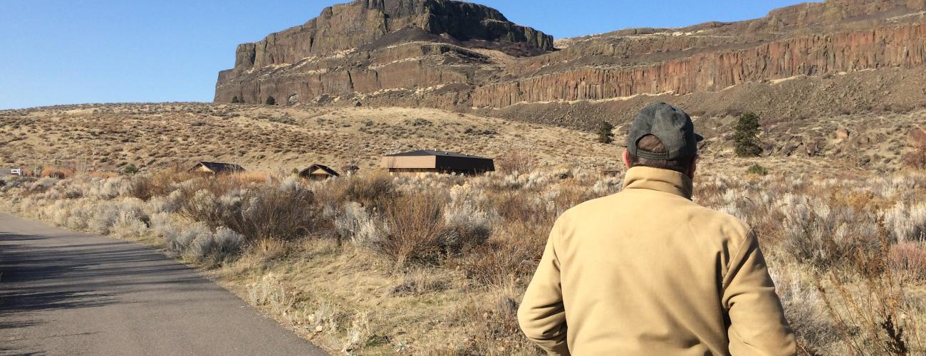 Hiker walking, basalt cliffs ahead.