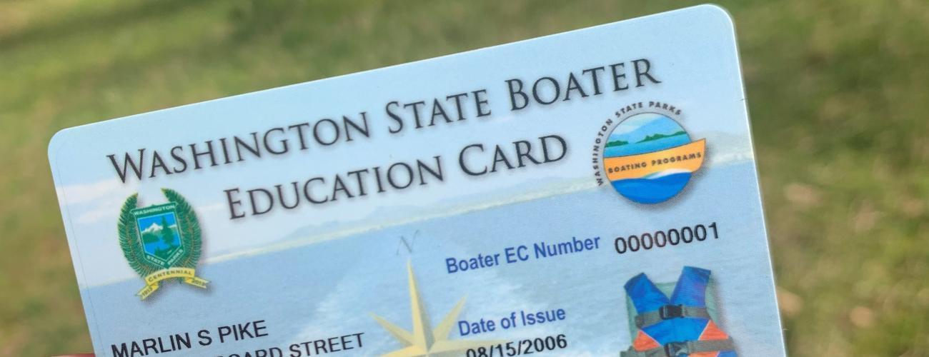 a hand holding up a mandatory boater education card with placeholder information