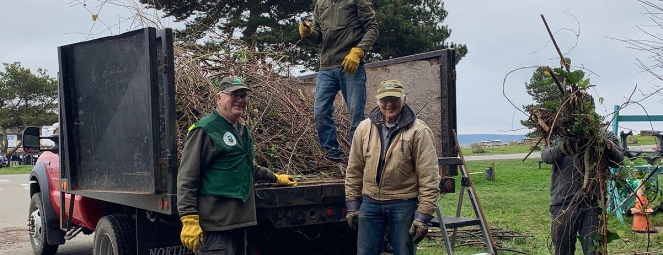 Group photo of volunteers loading debris in a truck at Fort Worden