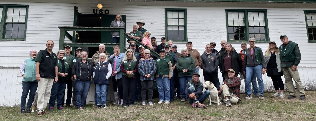 group of volunteers posing for a photo in front of a white building on a hill.