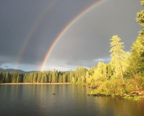 A double rainbow over a lake with cloudy skies