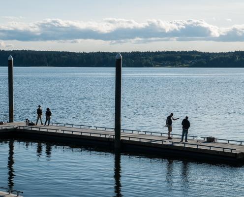 Four people fish from a dock.