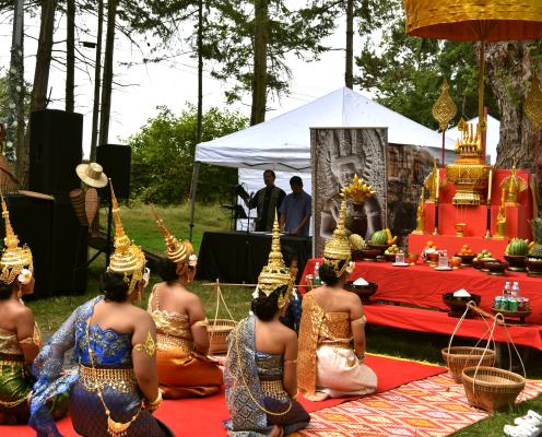 A group of people dressed in Cambodian traditional clothing kneeling and praying to the Buddah