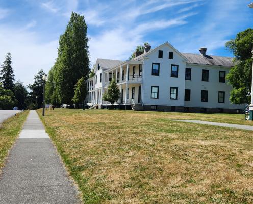 Sidewalk view of some of the white barrack houses at Fort Worden State Park on a beautiful sunny, blue-sky day