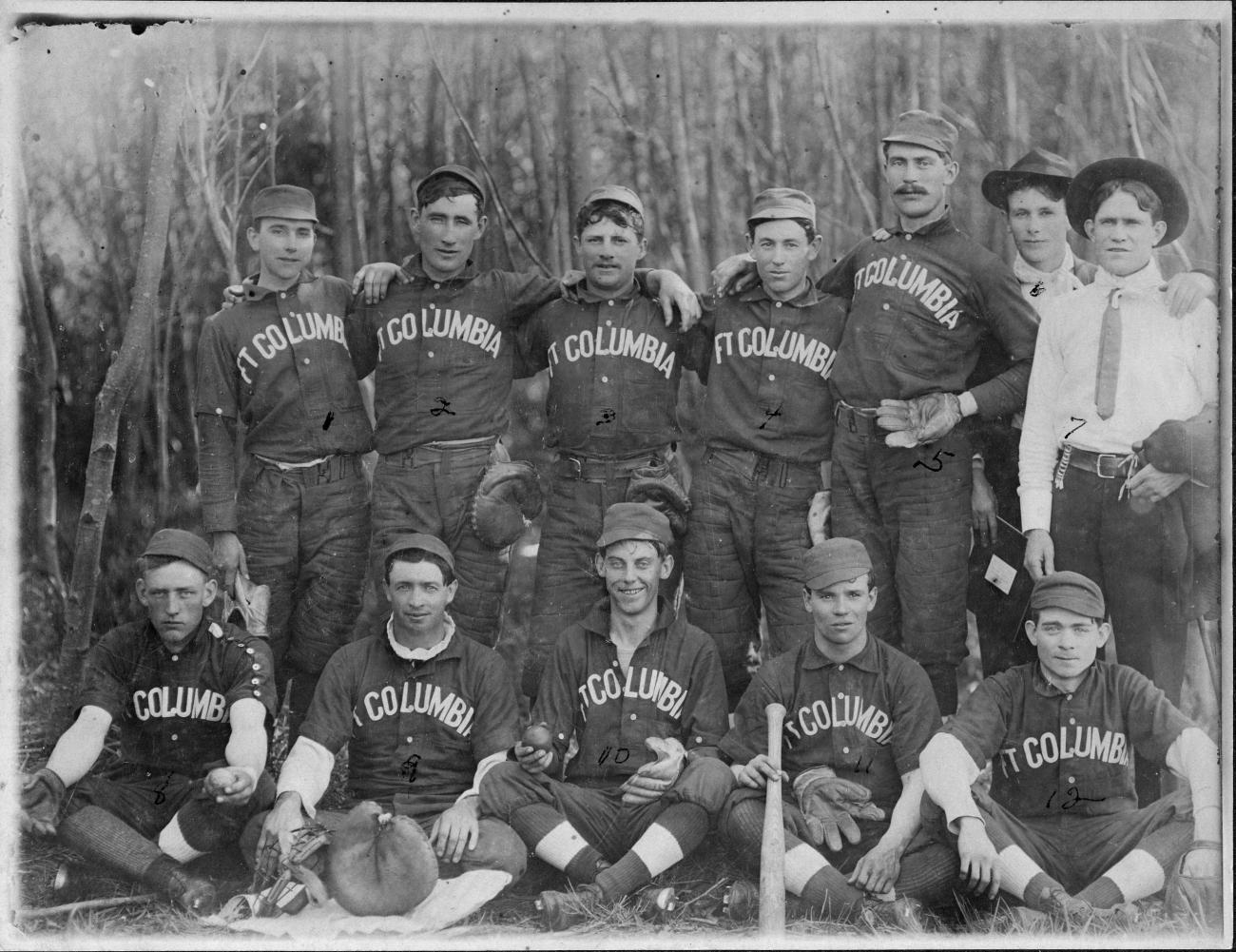 A black and white photograph of baseball players sitting in rows in their uniforms.