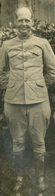 An old photo of a military colonel in uniform, standing at attention and smiling.