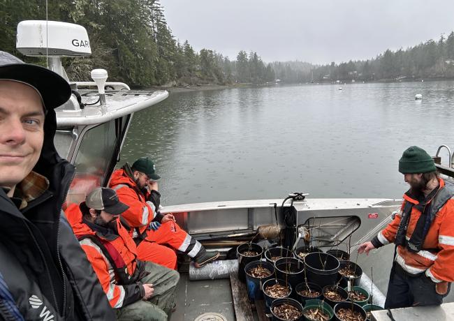 A selfie of arborists on a boat with small tree plantings.