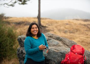 Hiker smiling with water and backpack.