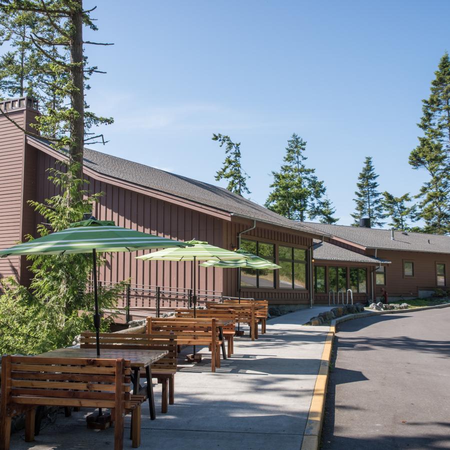 Cama Beach café building with visible tables, benches, and umbrellas. 