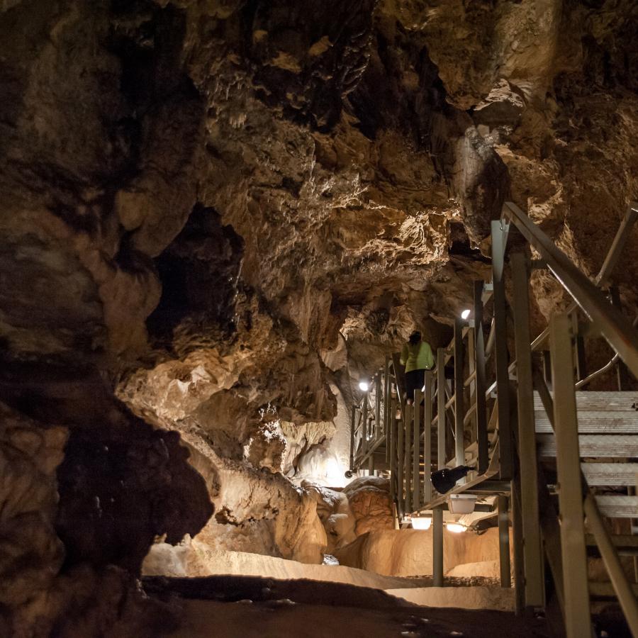 A metal walkway sits above the formations inside of the cave.