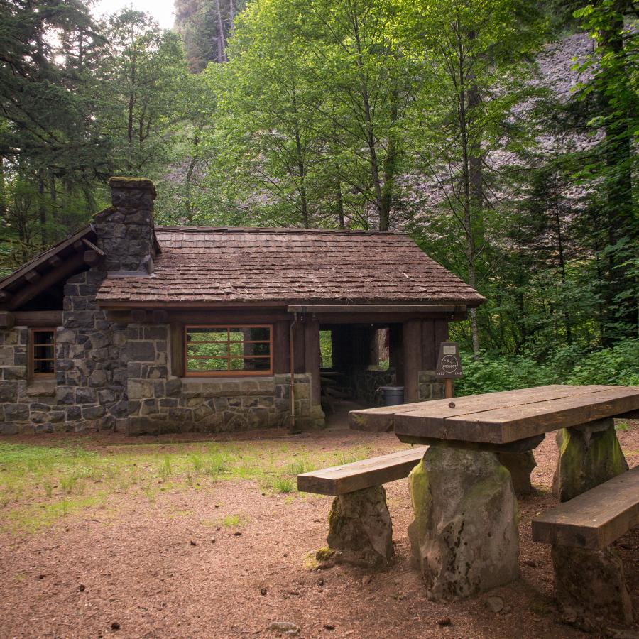 A picnic shelter and a bench surrounded by trees at Beacon Rock State Park.