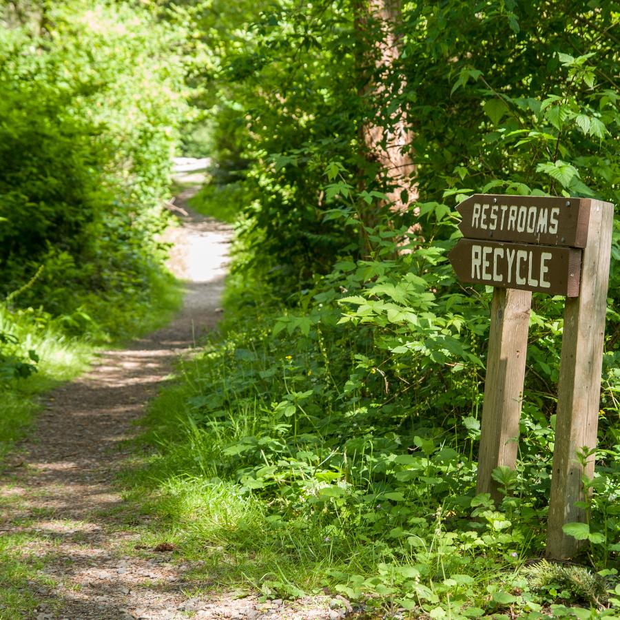 A restroom and recycle sign pointing to the trail in Dash Point State Park.