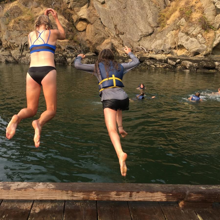 two girls jumping off dock onto cool bluegreen water