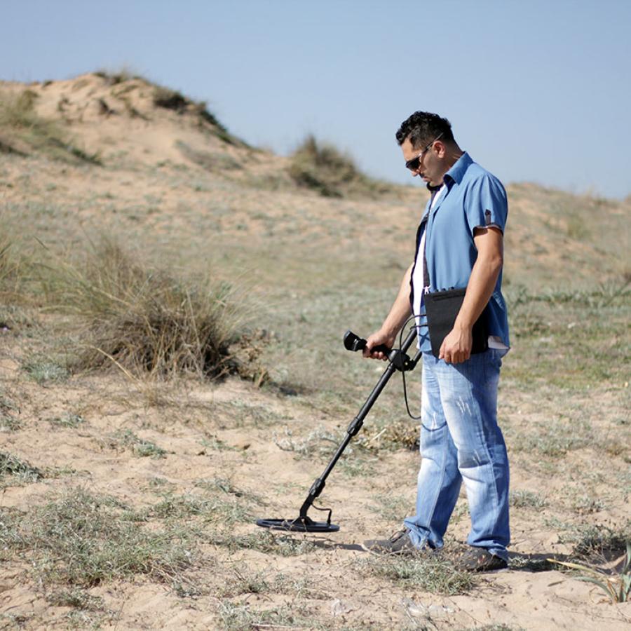 Man metal detecting outdoors.