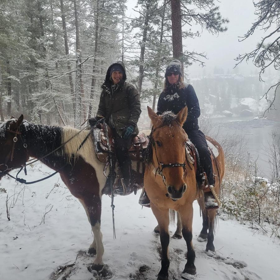 Horses and Riders in the snow with a view of the river