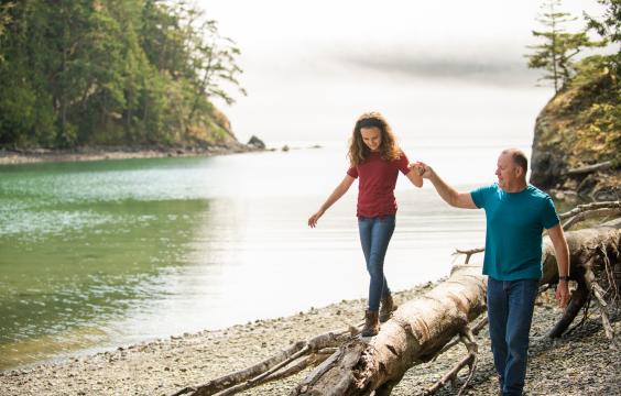 Father and daughter walk along the beach.