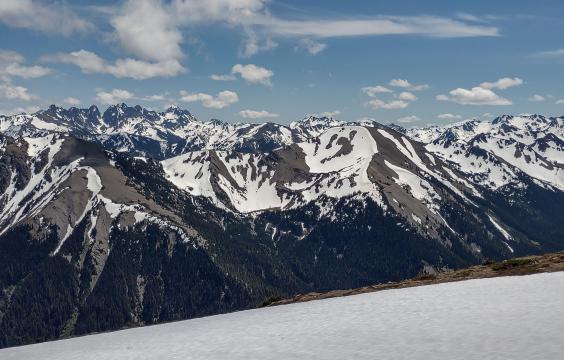 Snowy mountain range sits beyond field of snow