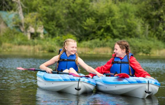 Two girls in Kayaks wearing life jackets