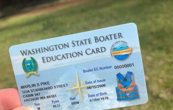a hand holding up a mandatory boater education card with placeholder information